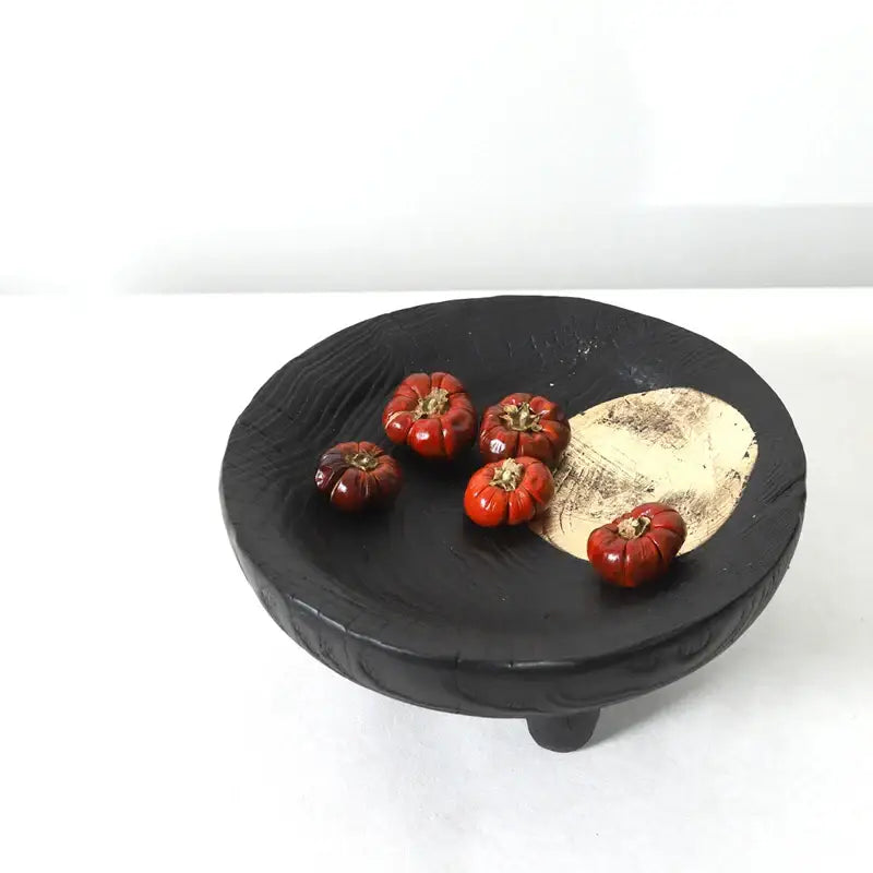 Black ceramic corner tray with wood grain texture and gold-toned inlay holding red decorative pumpkins decorbites imitation wood