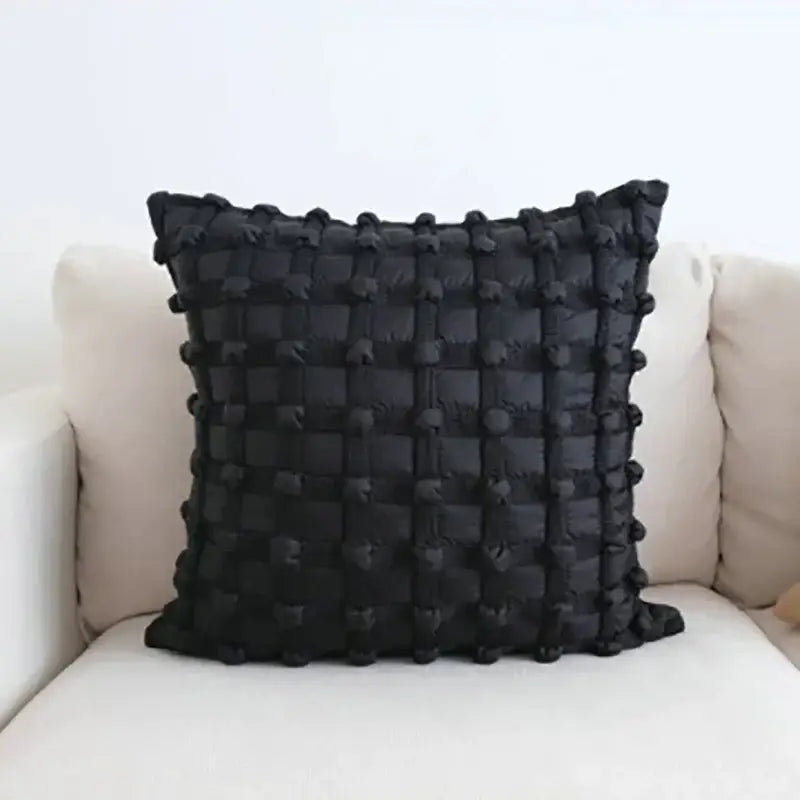 Black dot bubble quilted cushion cover with textured grid pattern and pom pom accents for stylish home decor