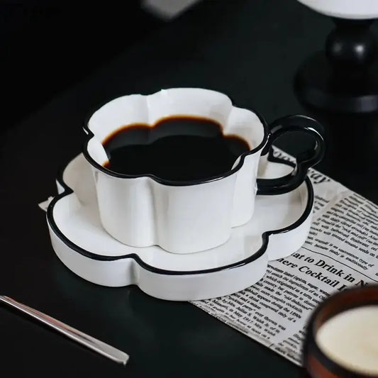 White ceramic mug set with black edged flower design featuring a black rim and handle with matching saucer