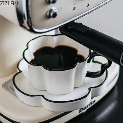 White ceramic coffee cup with black edged rim and handle filled with dark espresso from black edged flower mug set