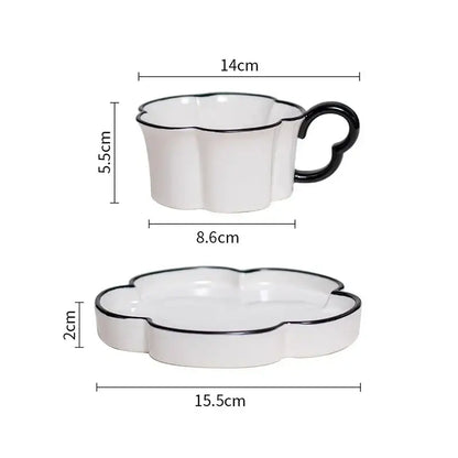 White ceramic mug set with black edged flower design featuring a heart-shaped handle on cup and matching saucer