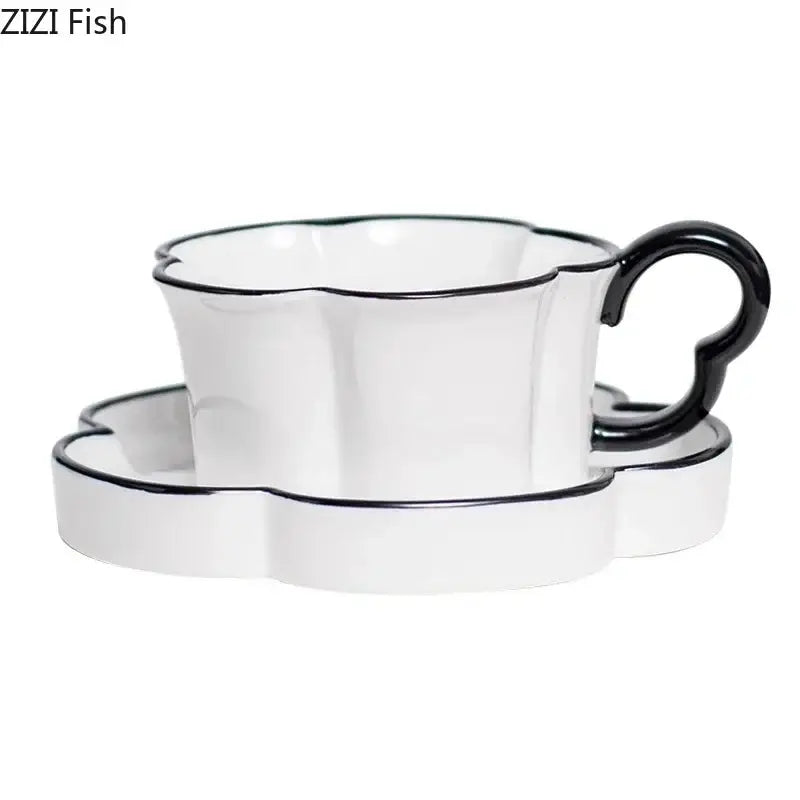White ceramic mug set with black edged flower design featuring a black rim and heart-shaped handle with matching saucer