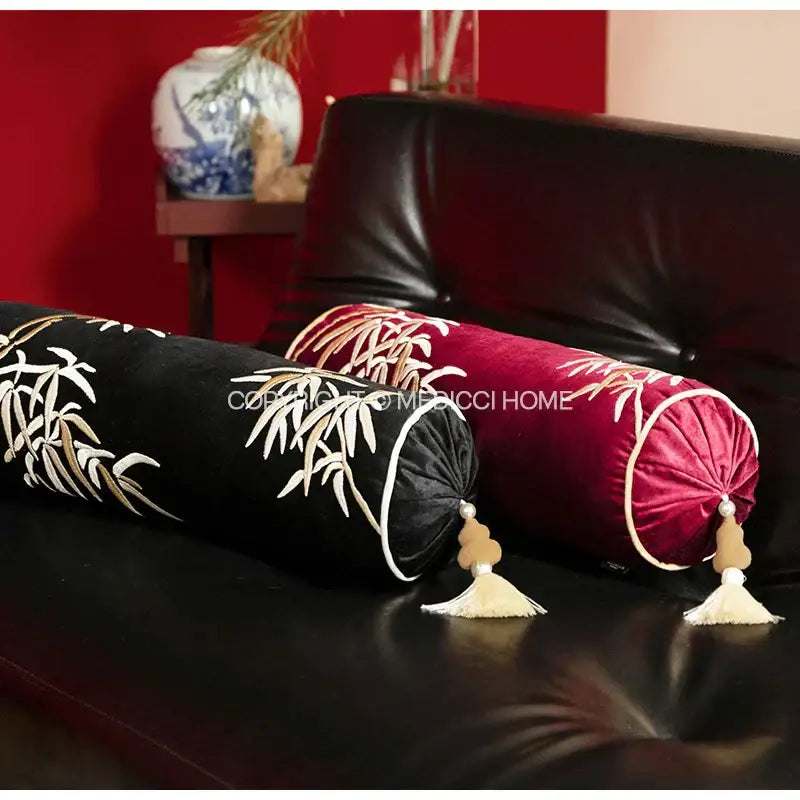 Two velvet bolster pillow covers in black and red with embroidered black and gold bamboo leaves and tassels