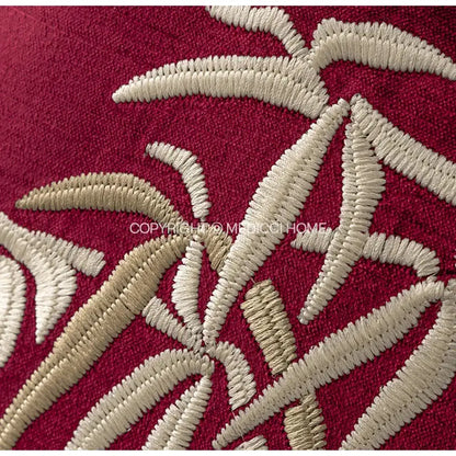 A plush red bolster pillow cover with intricate cream embroidered bamboo leaves for bedroom pillow covers