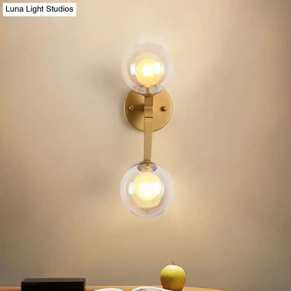 Gold-toned black and gold bubble wall sconce with two clear glass globe shades for bedroom lighting