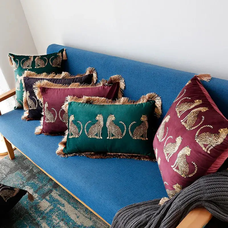 Set of emerald green and burgundy velvet throw pillow covers with gold leopard embroidery and fringed tassels for living room