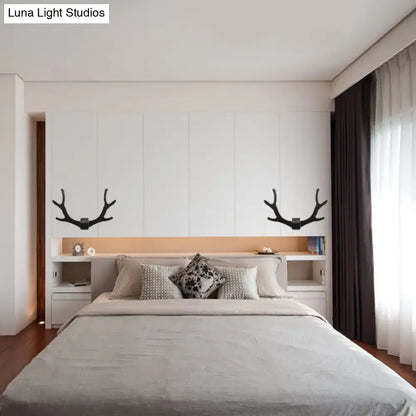 Black metallic antler sconce wall mounted lighting fixture symmetrically mounted above the bedroom bed