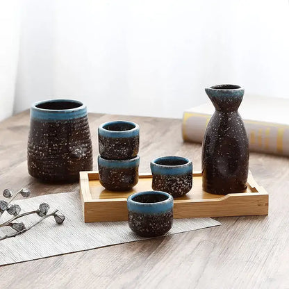 Black speckled ceramic wine sake set with heater featuring tall bottle, cylindrical container, and cups on wooden tray decorbites ceramic wine