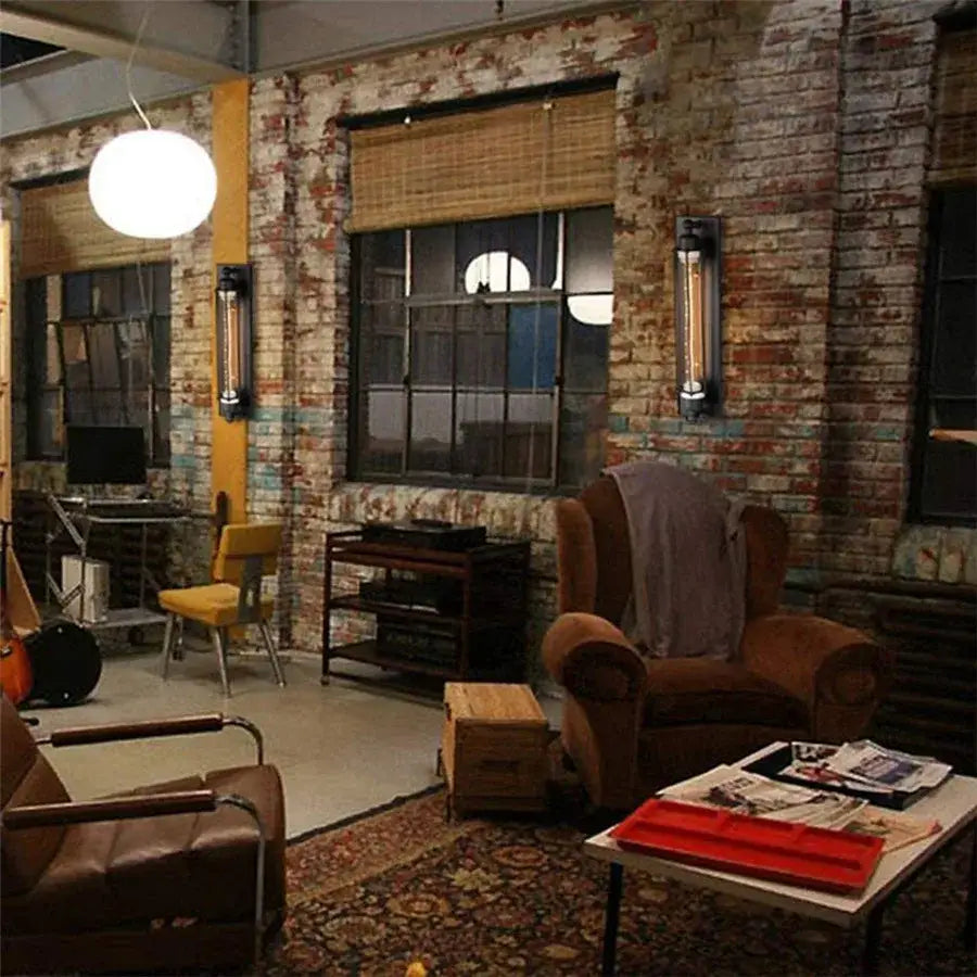 Brown leather armchair with rolled arms and gray blanket paired with decorbites black vintage industrial wall sconce for bedroom