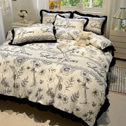 Cream-colored bedding set with black white printed floral and shower of flowers script design with ruffled edges decorbites black white