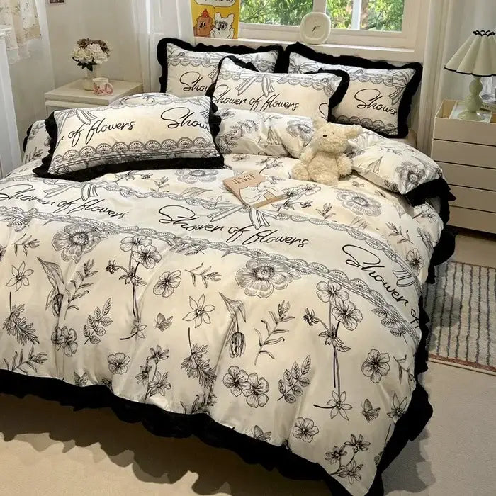 Cream-colored bedding set with black white printed floral and shower of flowers script design with ruffled edges decorbites black white