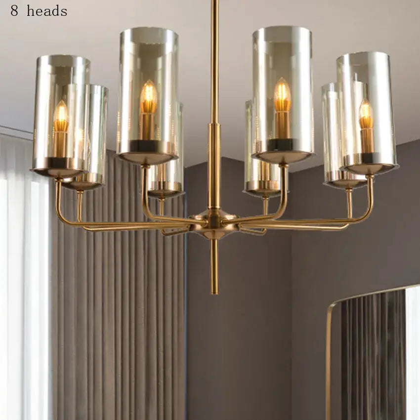 Brass-finished decorbites glass chandelier with eight cylindrical glass shades and warm-toned bulbs for kitchen island lighting