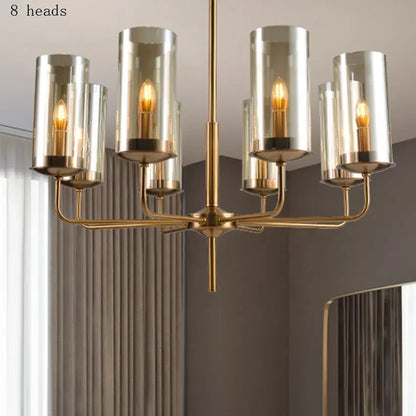 Brass-finished decorbites glass chandelier with eight cylindrical glass shades and warm-toned bulbs for kitchen island lighting