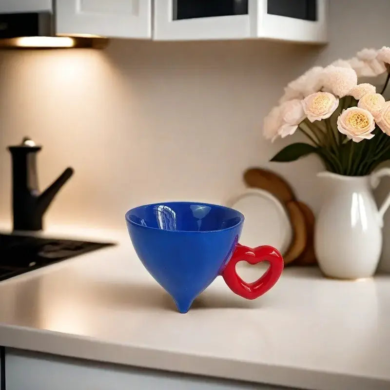 A vibrant blue heart shape ceramic mug with a red decorbites heart shape handle for fruit juice use