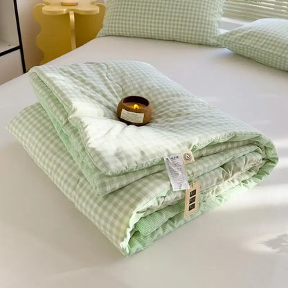 A soft light green and white gingham decorbites cotton summer quilt with soybean fiber filling folded on a bed
