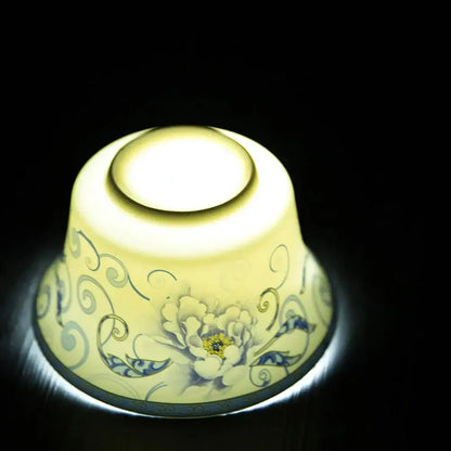 A glowing inverted porcelain tea cup with a blue floral and white peony design from a tea cup set for dining room use