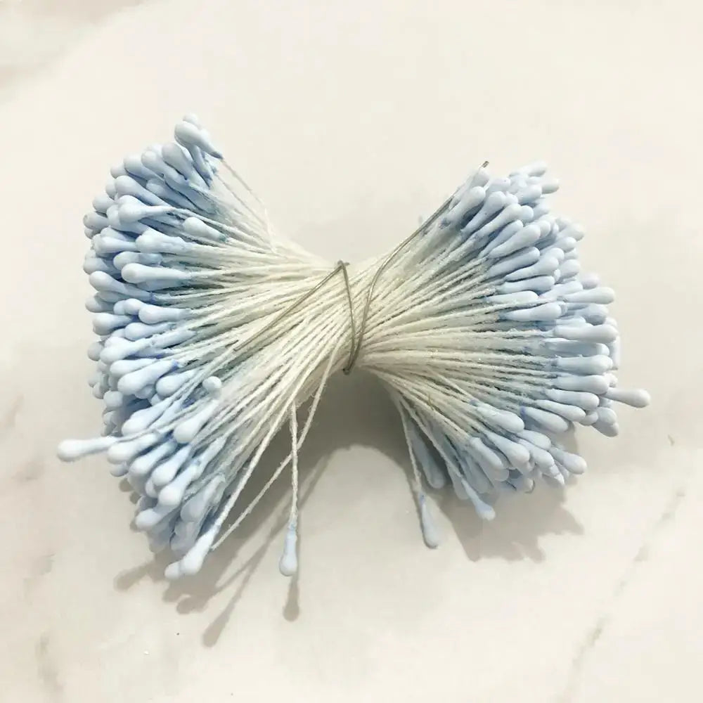 A bundle of light blue cotton swabs tied with string resembling decorbites blue flower cherry stamen berries decor
