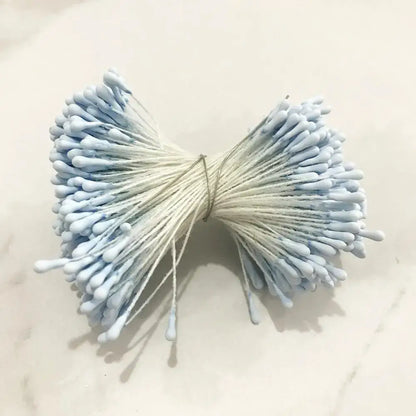 A bundle of light blue cotton swabs tied with string resembling decorbites blue flower cherry stamen berries decor