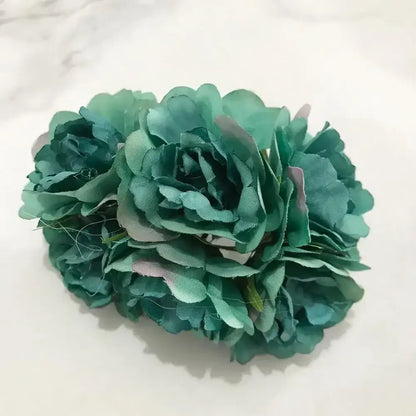 A cluster of teal fabric blue flower stamen berries with layered petals and subtle pink accents for cake decor