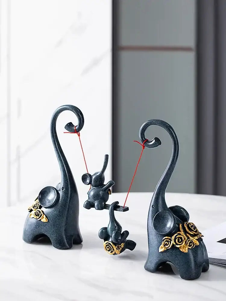 Dark gray resin elephant family swing sculpture with gold rose accents and curled trunks for living room decor