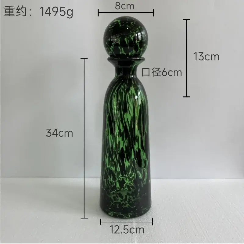 A tall slender green glass decanter with swirling marbled pattern and rounded stopper for decorbites leopard print decor