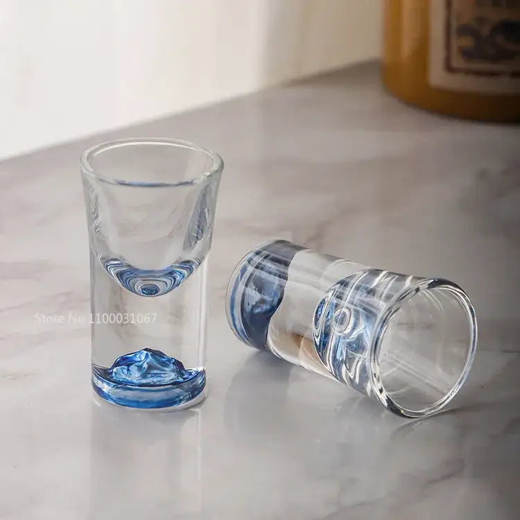 Clear glass decorbites blue sake shot glasses with intricate blue swirls molded into the base and rim