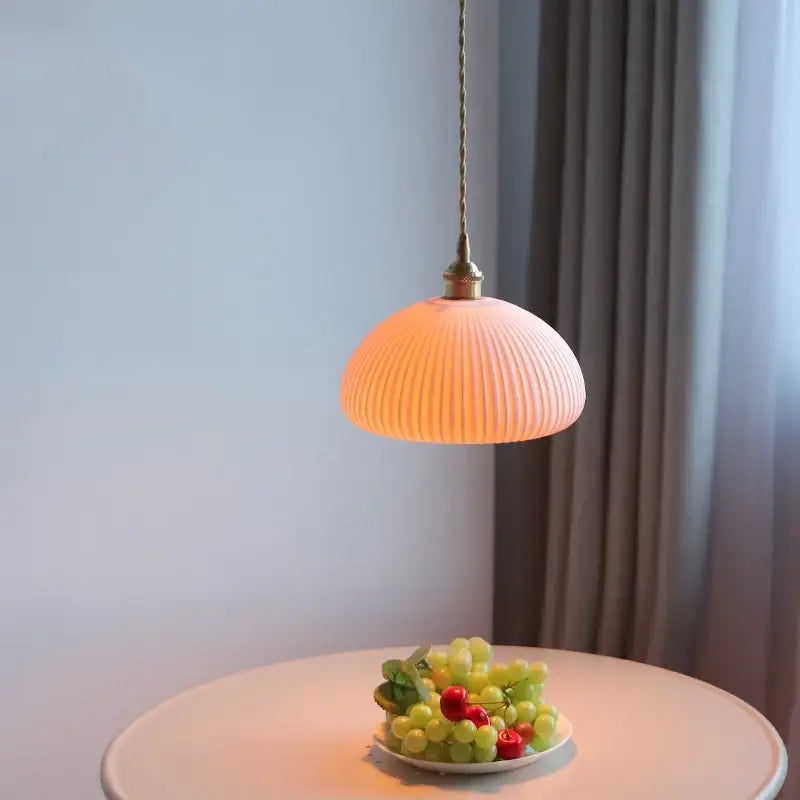 A soft peach-colored ribbed glass pendant lamp with brass-finished metal fixture for decorbites ceramic led pendant