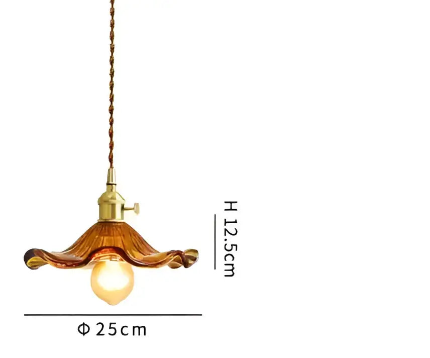A warm amber glass decorbites pendant light with brass fixture and twisted cord for bedroom decor