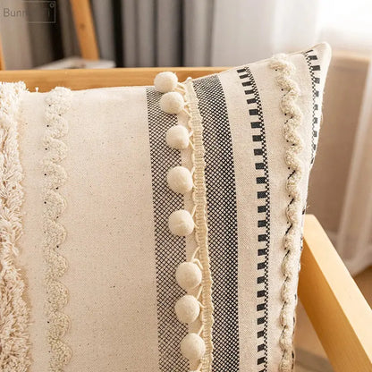 Cream-colored decorbites bohemian beige cushion cover with black and white stripes and tasseled pom-poms for living room decor