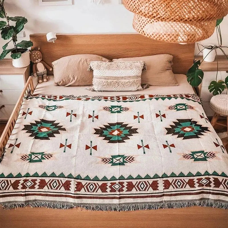 A cream-colored woven bohemian sofa blanket with teal rust brown tribal patterns and vintage plaid design decorbites
