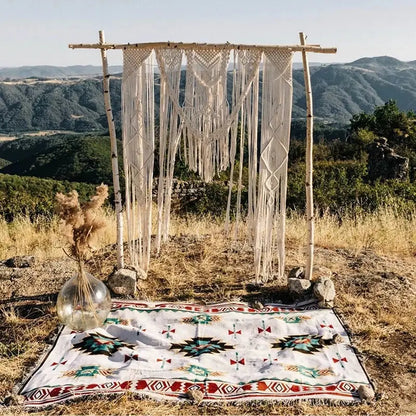 Cream-colored macramé wedding arch with intricate knotwork and tassels complements vintage plaid bohemian sofa blanket decorbites