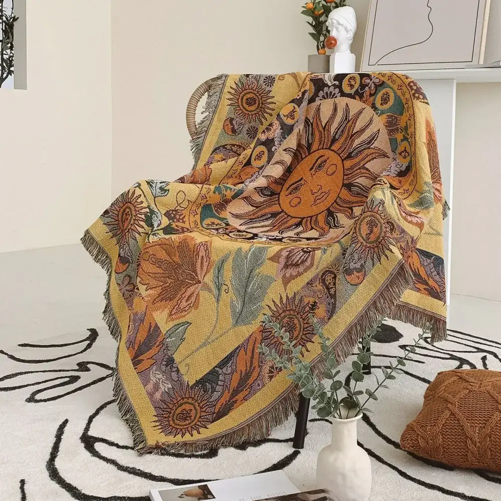 A vibrant yellow decorbites bohemian camping blanket featuring sun and floral patterns with fringed edges for living room decor