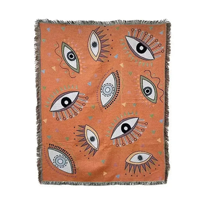 Orange woven throw blanket with stylized eyes pattern in black white and beige by decorbites bohemian classic design