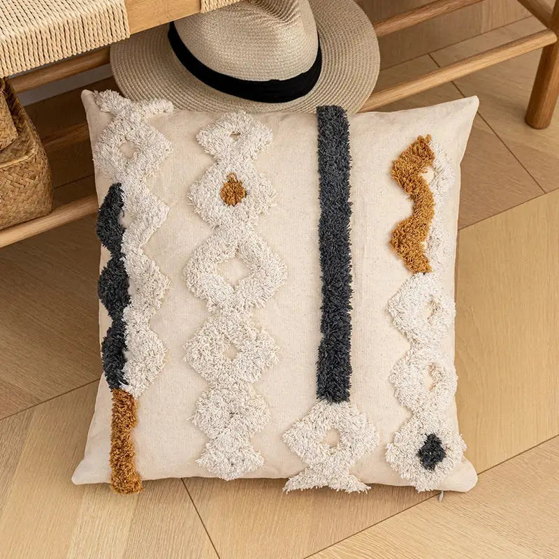 Cream-colored bohemian cotton cushion cover with textured tufted black and caramel geometric patterns for living room decorbites
