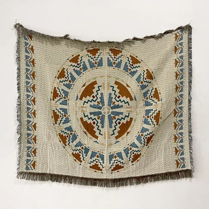 Beige woven bohemian throw blanket with a central blue orange green geometric pattern and fringed edges from decorbites