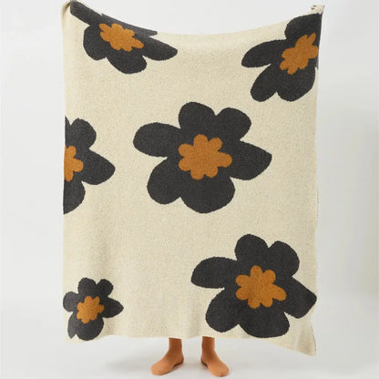 Cream-colored plush bohemian flower knitted throw blanket with bold black and orange floral decorbites design for bedroom decor