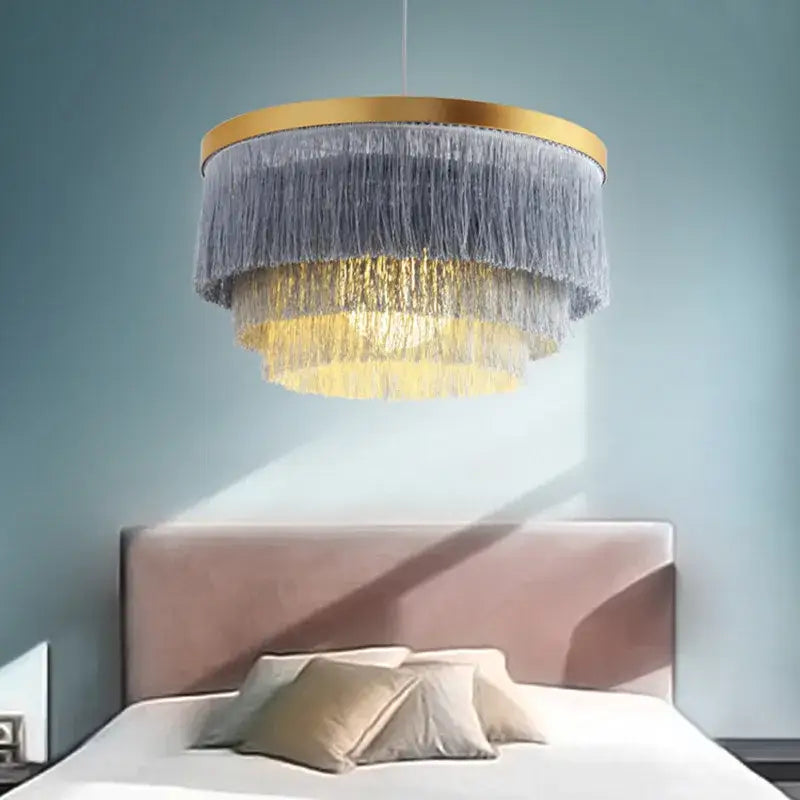 Bohemian gold tiered chandelier with gold-toned frame and cascading gray and golden fringes for bedroom decor