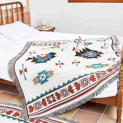 Cream-colored woven bohemian jacquard sofa blanket with bold teal red and black geometric patterns and fringed edges