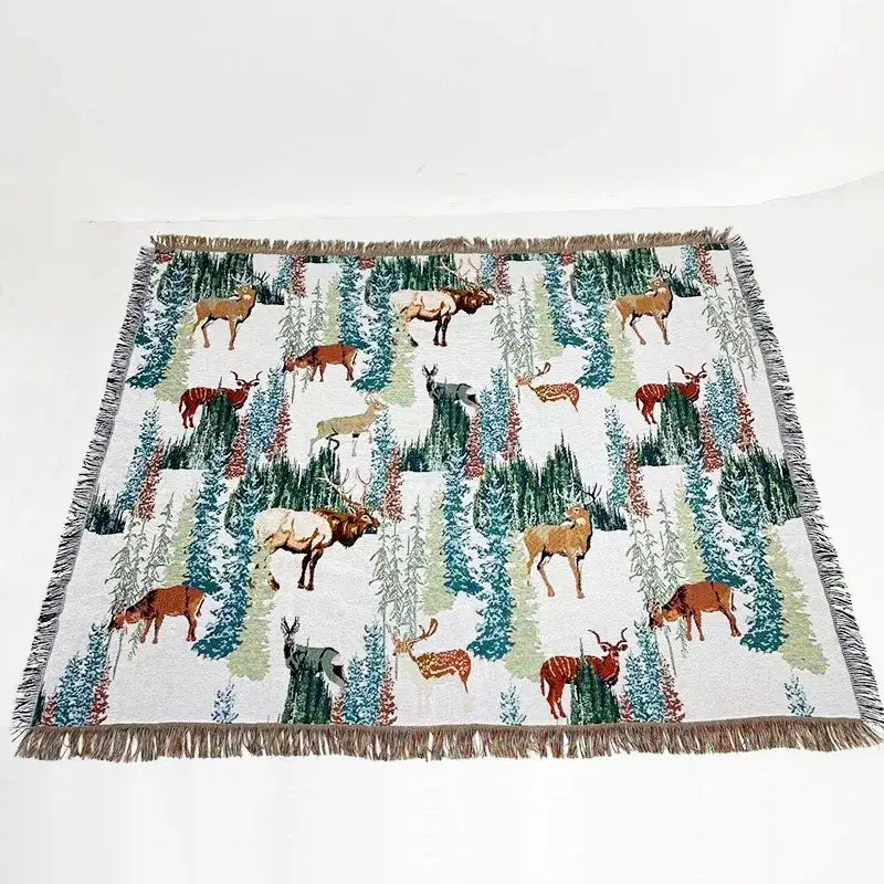 White woven bohemian jacquard sofa blanket with brown green teal deer and evergreen pattern and fringed edges