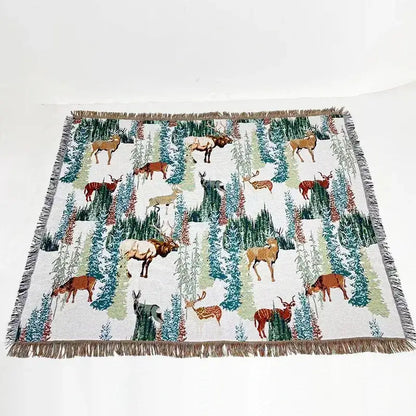 White woven bohemian jacquard sofa blanket with brown green teal deer and evergreen pattern and fringed edges