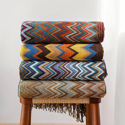 Stacked decorbites bohemian knit tassel blankets with vibrant multicolored zigzag patterns and fringe detailing