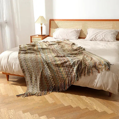 A cozy earth-toned bohemian knit tassel blanket with multicolored zigzag pattern and fringed edges for decorbites decor
