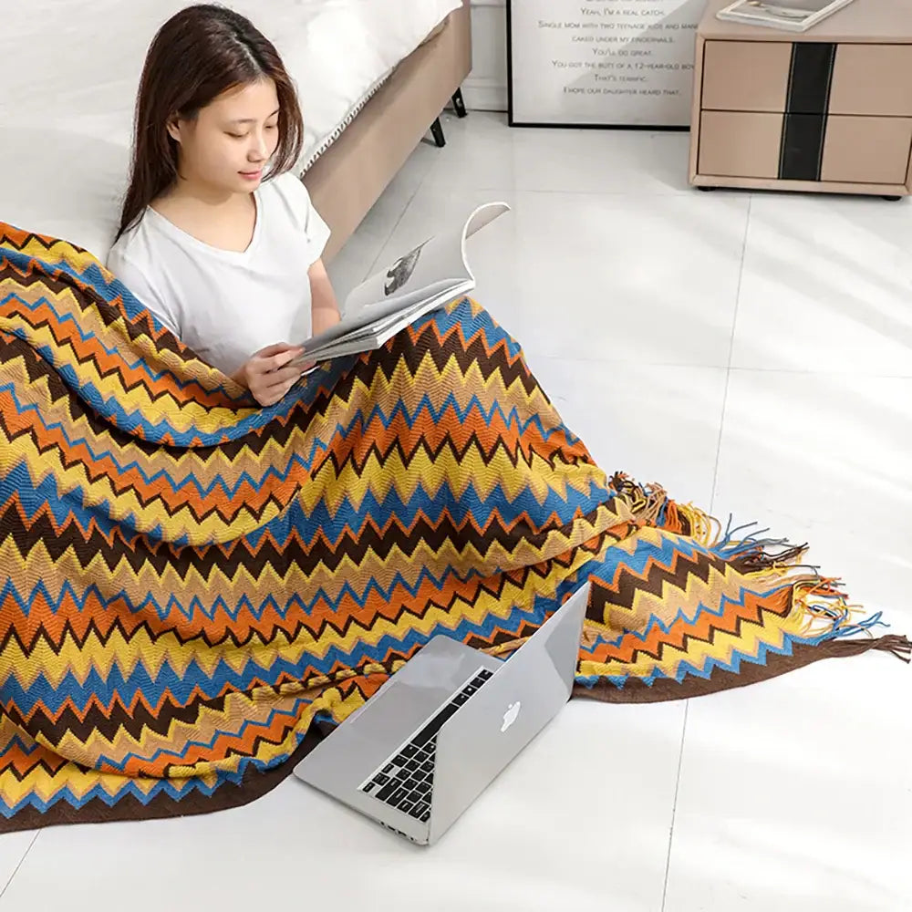 Vibrant bohemian knit tassel blanket with multicolored zigzag pattern in orange yellow blue and brown for decorbites decor