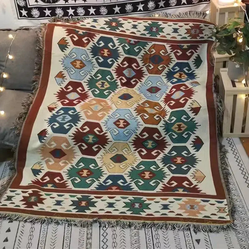A cozy cream-colored decorbites bohemian knit throw blanket with red and blue geometric pattern and fringed edges