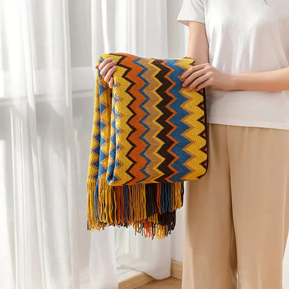 Bohemian knitted blanket featuring a vibrant multicolor zigzag pattern in yellow orange blue and brown with fringe