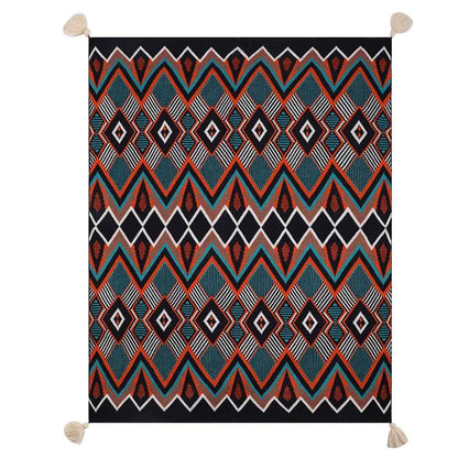 A bohemian knitted throw blanket with bold teal orange black and white geometric pattern and cream tassels at corners