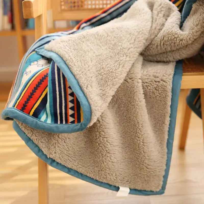 A cozy beige sherpa sofa blanket with colorful striped pattern and teal trim made of winter coral fleece for living room use
