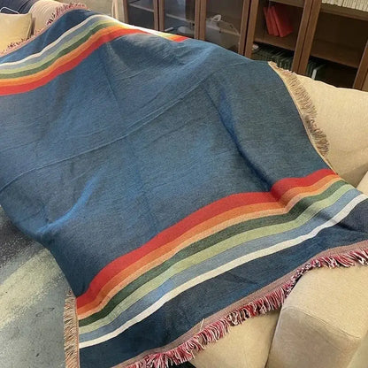 A cozy blue woven bohemian nordic leisure throw with vibrant rainbow stripes and fringed edges for bedroom decorbites