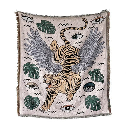 Beige woven decorbites bohemian outdoor blanket with winged tiger graphic and green monstera leaves on textured background