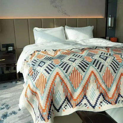 A cozy cream-colored bohemian striped knit throw blanket with bold orange navy blue and teal geometric patterns